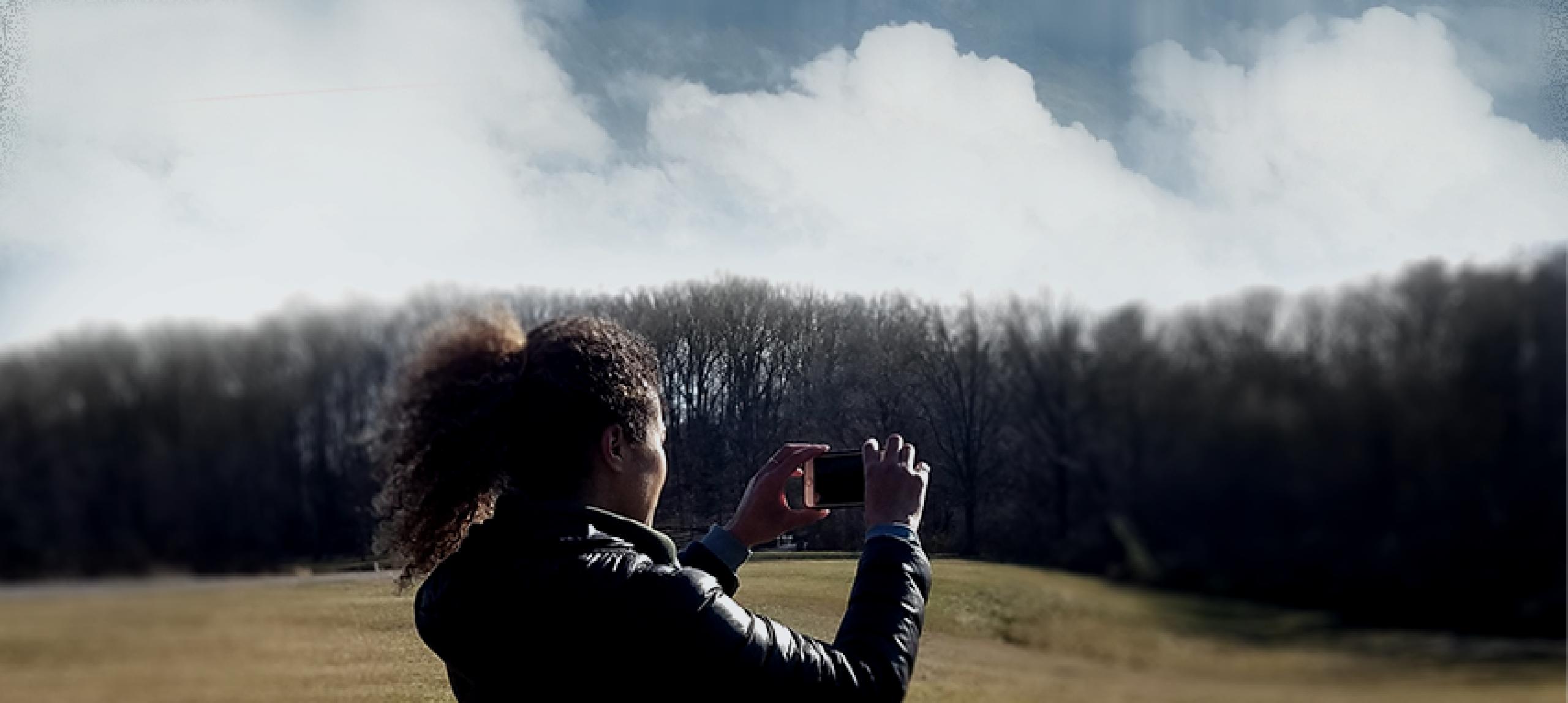 Photo of woman standing in a field taking a photograph