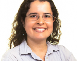 Portrait photo of smiling woman wearing glasses and with dark curly hair